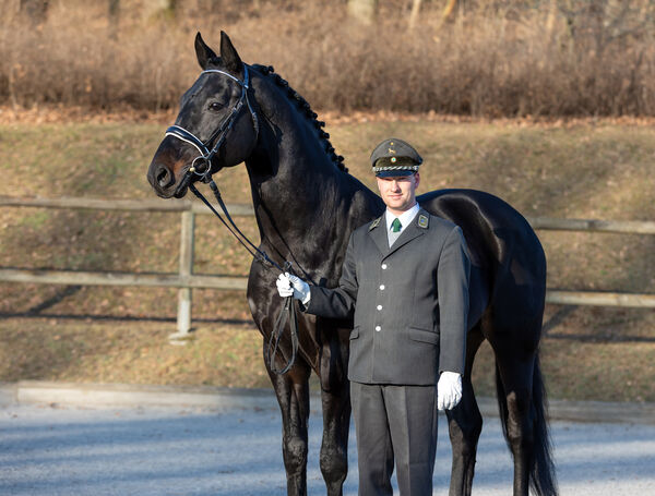 Ein Mann mit einem Pferd an der Hand schaut in die Kamera