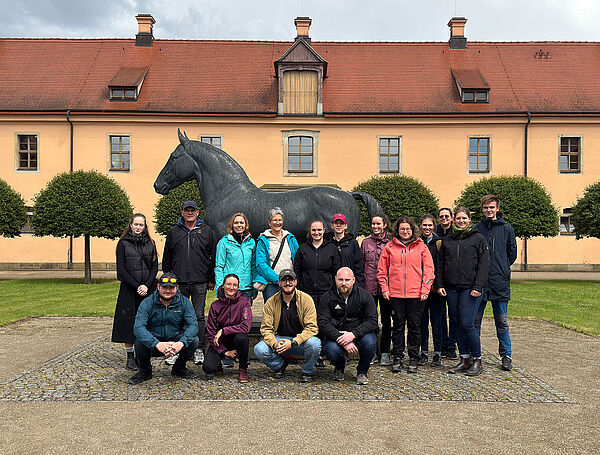Viele Personen gruppieren sich vor einer Pferdestatue