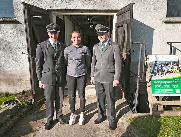 Drei Personen stehen vor einer geöffneten Stalltür